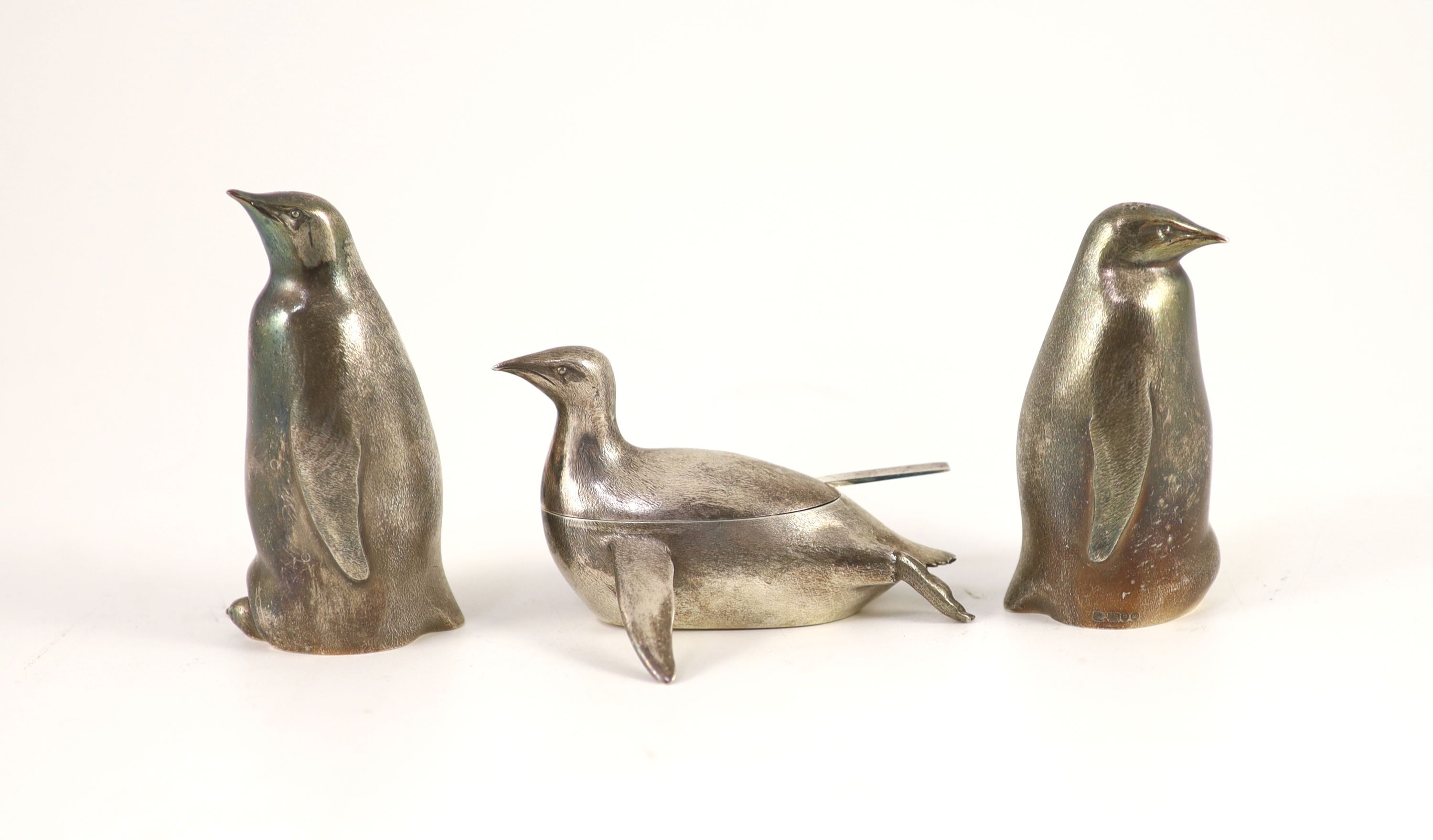 A modern textured silver novelty three piece condiment set, modelled as three penguins, two standing, one laying down